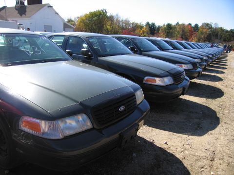 1991 Ford LTD Crown Victoria - Multiple Ford Crown Victoria police cars lined up in an outdoor lot under a clear sky.