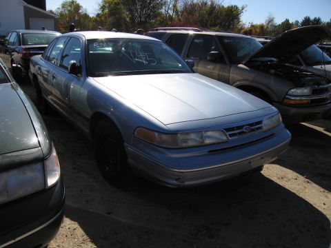 1991 Ford LTD Crown Victoria - A light blue Ford Crown Victoria is parked in a lot with other vehicles, one with its hood open.