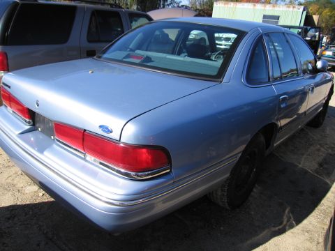 1991 Ford LTD Crown Victoria - The rear of a blue sedan is visible, parked outdoors next to another vehicle.