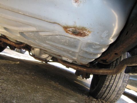 1991 Ford LTD Crown Victoria - The underside of a vehicle reveals a rusty fuel tank and exhaust system, with a differential visible.