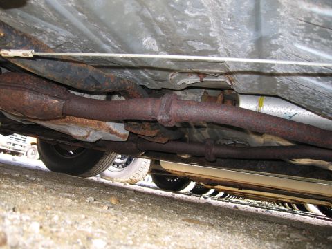 1991 Ford LTD Crown Victoria - The underside of a car, focusing on the rusted exhaust system and undercarriage components.