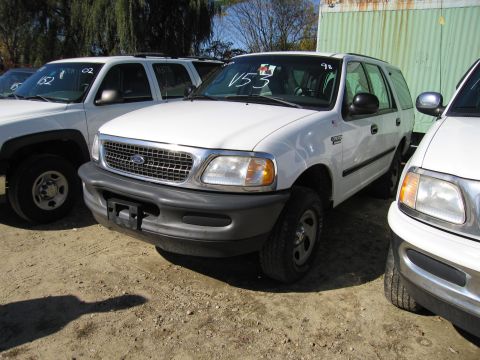 1991 Ford LTD Crown Victoria - White Ford Expedition SUV parked outdoors with other vehicles. VIN tag V53 is visible on the windshield.