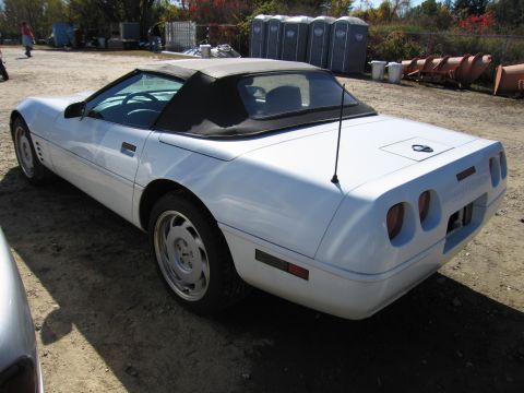 1991 Ford LTD Crown Victoria - Rear view of a white convertible sports car, likely a C4 Corvette, parked outdoors.