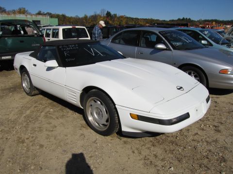 1991 Ford LTD Crown Victoria - A white convertible sports car is parked in a lot with other vehicles. Text is written on the windshield.