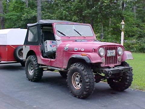 1985 Ford Bronco - This red Jeep CJ-7 is towing a trailer and has a license plate that says 'BOOTS'.