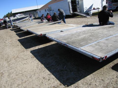 1991 Ford LTD Crown Victoria - Multiple trailers are parked on a dirt lot with several people gathered nearby.