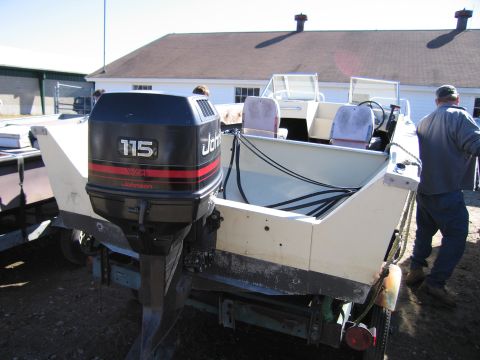 1991 Ford LTD Crown Victoria - A boat with a Johnson outboard motor is parked on a trailer.
