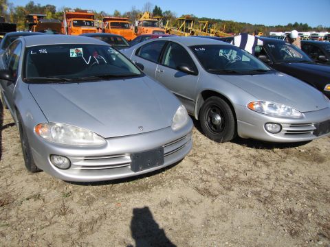 1991 Ford LTD Crown Victoria - Two silver sedans are parked next to each other in an outdoor lot, with construction vehicles in the background.