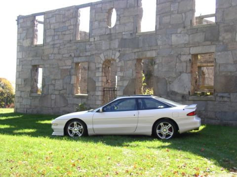 1996 Ford Probe - Side view of a white 1996 Ford Probe GT parked on grass near stone ruins.