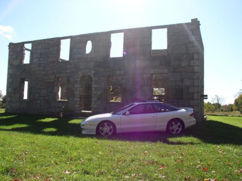 1996 Ford Probe - A white 1996 Ford Probe GT is parked in front of a weathered stone structure on a sunny day.