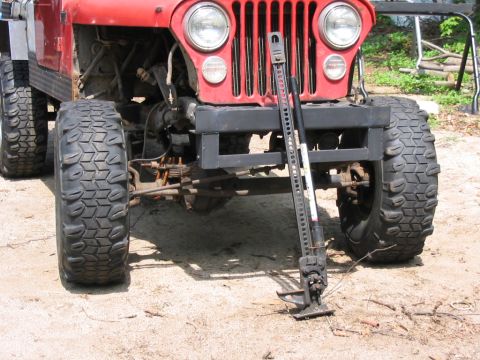 1985 Ford Bronco - Front view of a red Jeep CJ with off-road tires and a Hi-Lift jack.