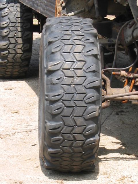 1985 Ford Bronco - A close-up view focuses on the tread of a off-road tire mounted on a vehicle.