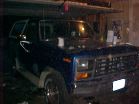 1985 Ford Bronco - Front view of a blue SUV with a prominent grille and headlights.