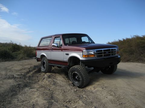 1996 Ford Bronco - This lifted 1996 Ford Bronco is shown off-road under a clear blue sky.
