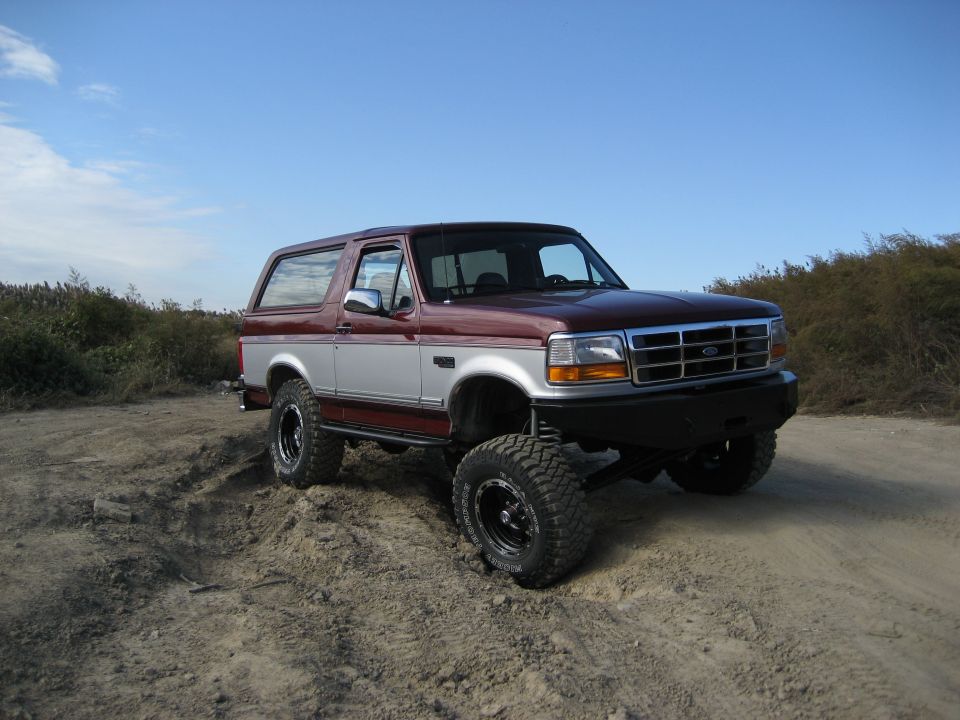 1996 Ford Bronco with aftermarket bumper and lift kit on dirt terrain