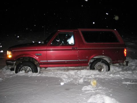 1994 Ford Bronco - Red 1994 Ford Bronco partially buried in snow during nighttime.