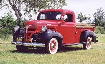 1991 Ford Bronco - This vintage red pickup truck is shown from a three-quarter front view, parked outdoors on a grassy field.