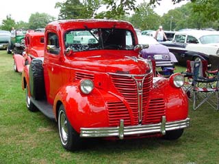 1991 Ford Bronco - Front view of a vintage red pickup truck, likely from the 1940s, parked on grass.