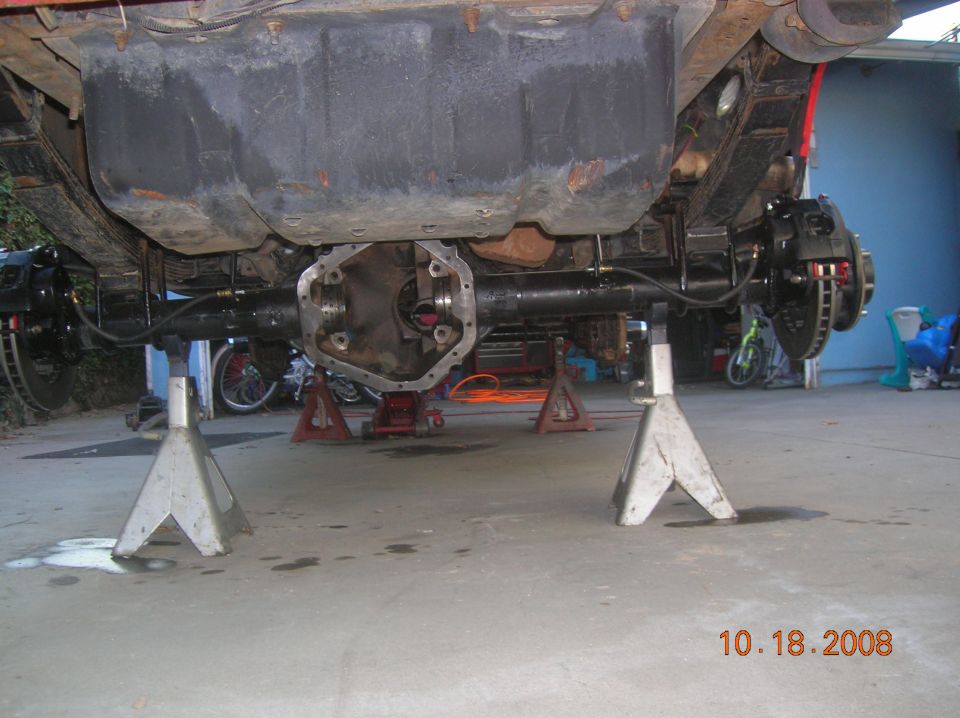 Rear axle assembly on jack stands, showing differential housing, brake calipers, and leaf springs