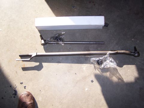 1986 Ford Bronco - Steering linkage components are laid out on a concrete surface, with a white box and a shoe in view.