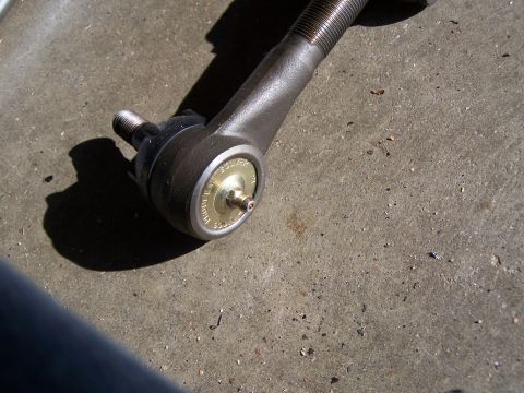 1986 Ford Bronco - Close-up of a steering tie rod end with a threaded adjuster sleeve and a tapered stud, showing a gold-colored grease Zerk fitting with 'PRO…
