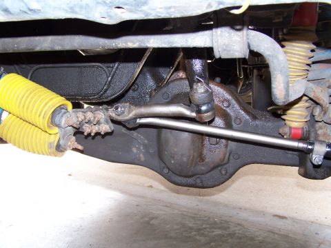 1986 Ford Bronco - Undercarriage view of a 1986 Ford Bronco, showing the front axle and suspension system with yellow shock absorbers.