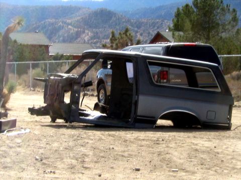 1996 Ford Bronco - The stripped body of a Ford Bronco sits on the ground, with another vehicle visible in the background.