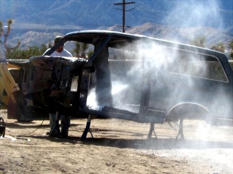 1996 Ford Bronco - A vehicle body is being cleaned with a pressure washer in an outdoor setting, with mountains in the background.
