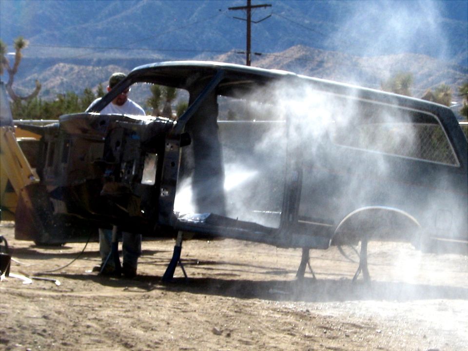 Car body being pressure washed outdoors, side view