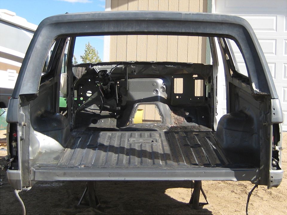 1996 Ford Bronco interior, stripped down, showing frame and body panels. Outdoor setting.