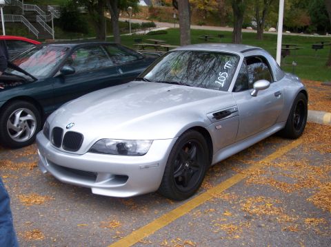 1996 Ford Probe - A silver BMW Z3 coupe is parked on asphalt with fallen leaves scattered around. The car has black wheels and a white sticker on the windshi…
