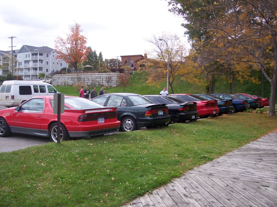 Red, green, black, and blue sports coupes parked in a row on grass.