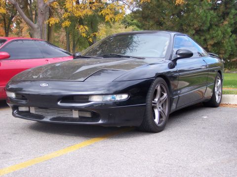 1996 Ford Probe - A black Ford Probe is parked in a lot with a red car partially visible behind it. The front of the black car shows a modified intercooler a…