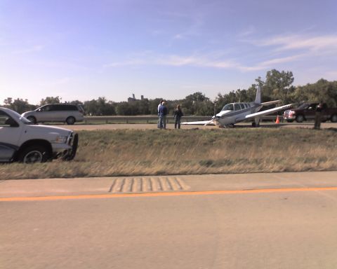 1995 Ford Bronco - A small airplane has landed on the side of a highway next to a ditch. Several people are standing around the aircraft and a few vehicles ar…