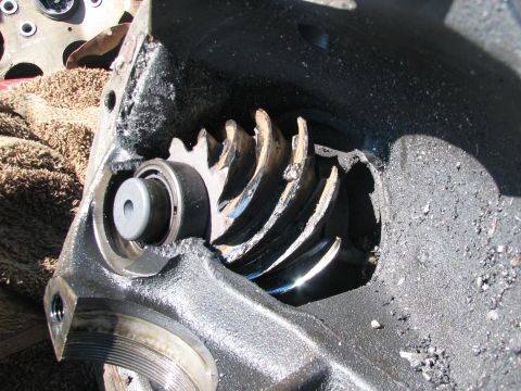 1979 Ford Bronco - A close-up view of a damaged differential housing with a ring gear and bearing visible. The metal casing is heavily coated in black grease…