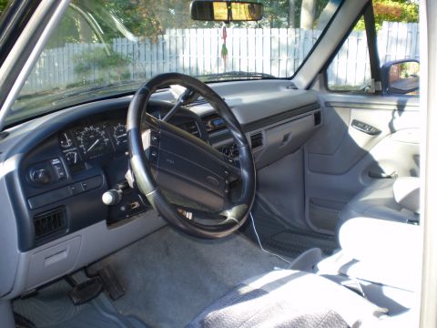 1996 Ford Bronco - The interior of a 1996 Ford Bronco is shown, with a focus on the driver's side dashboard, steering wheel, and part of the passenger seat. T…