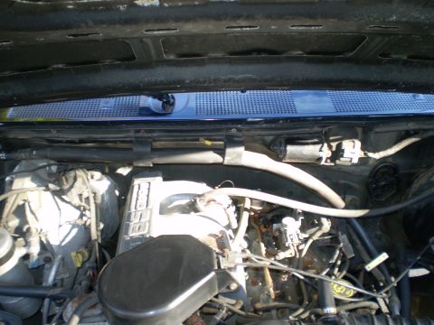 1996 Ford Bronco - The image shows a close-up view of the engine bay of a 1996 Ford Bronco. The hood is open, revealing the engine components, hoses, and wiri…
