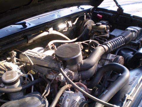 1996 Ford Bronco - The engine bay of a 1996 Ford Bronco is shown, with the hood open. Various engine components, hoses, and the air intake system are visible.