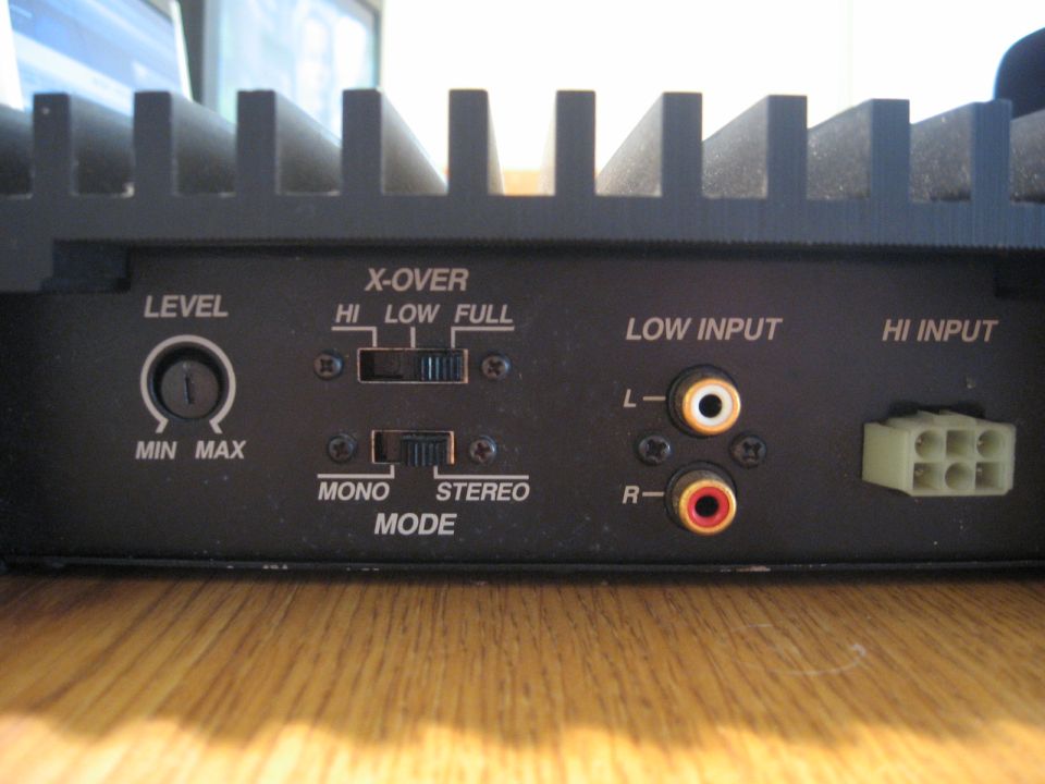 Rear panel of a car amplifier with labels and connectors.