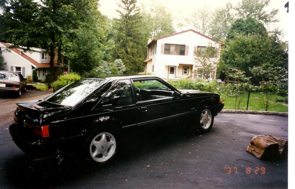 Black 1988 Ford Mustang coupe parked in a driveway.