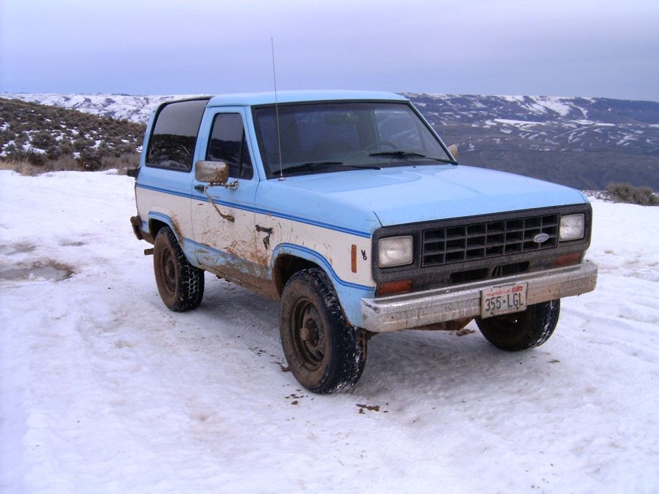 Light blue and white two-door SUV in a snowy, muddy landscape.
