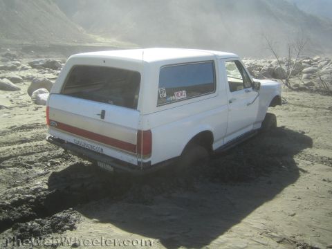 1990 Ford Bronco - Photo of a white Ford Bronco buried in mud at an off-road wash, not a technical document.