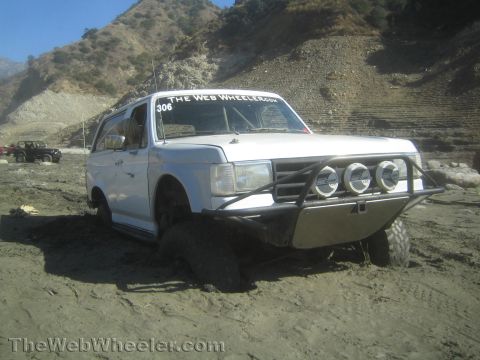 1990 Ford Bronco - Photo of a white lifted Ford Bronco in a canyon mud pit, not a technical document.