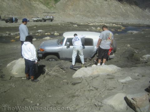 1990 Ford Bronco - Photo of a silver FJ Cruiser bogged in mud with bystanders, not a technical document.