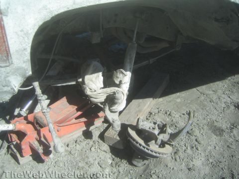 1990 Ford Bronco - Photo of jack, tools and parts beneath a truck during a repair, not a technical document.