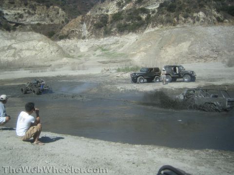 1990 Ford Bronco - Photo of off-road vehicles and spectators at a canyon mud pit, not a technical document.