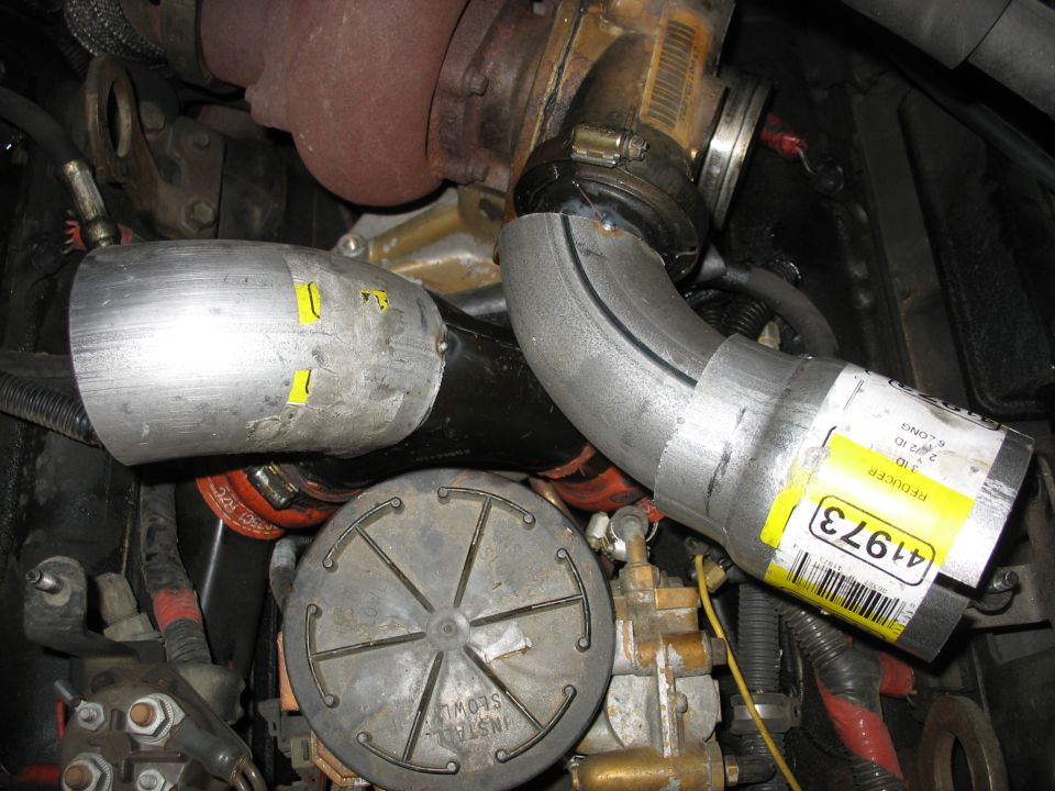 Close-up of diesel engine exhaust pipes and a reducer with yellow labels.