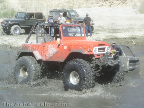 1990 Ford Bronco - Photo of an orange FJ40 Land Cruiser in a water crossing, not a technical document.