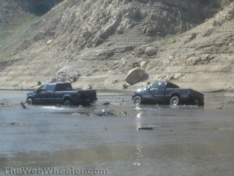 1990 Ford Bronco - Photo of two pickups crossing a flooded wash, not a technical document.