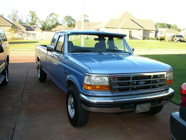 Blue 1990s Ford F-150 pickup truck parked in driveway
